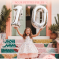 Séance photo d'anniversaire d'une petite fille en extérieur, souriante et portant une robe colorée.
